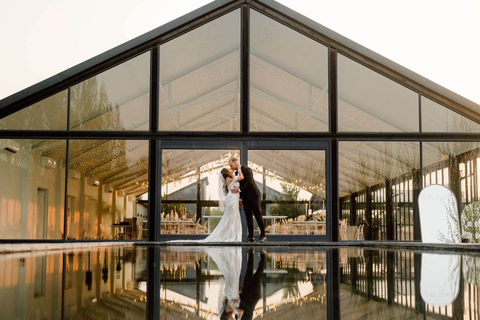 A couple kissing inside a glass wedding venue