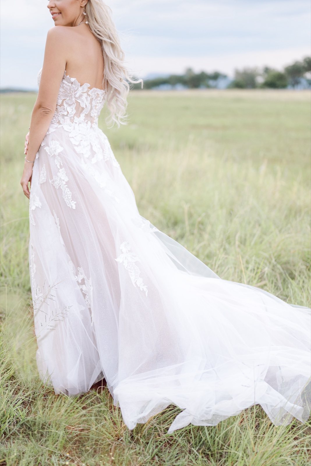 Bride walking through a field in a flowing dress