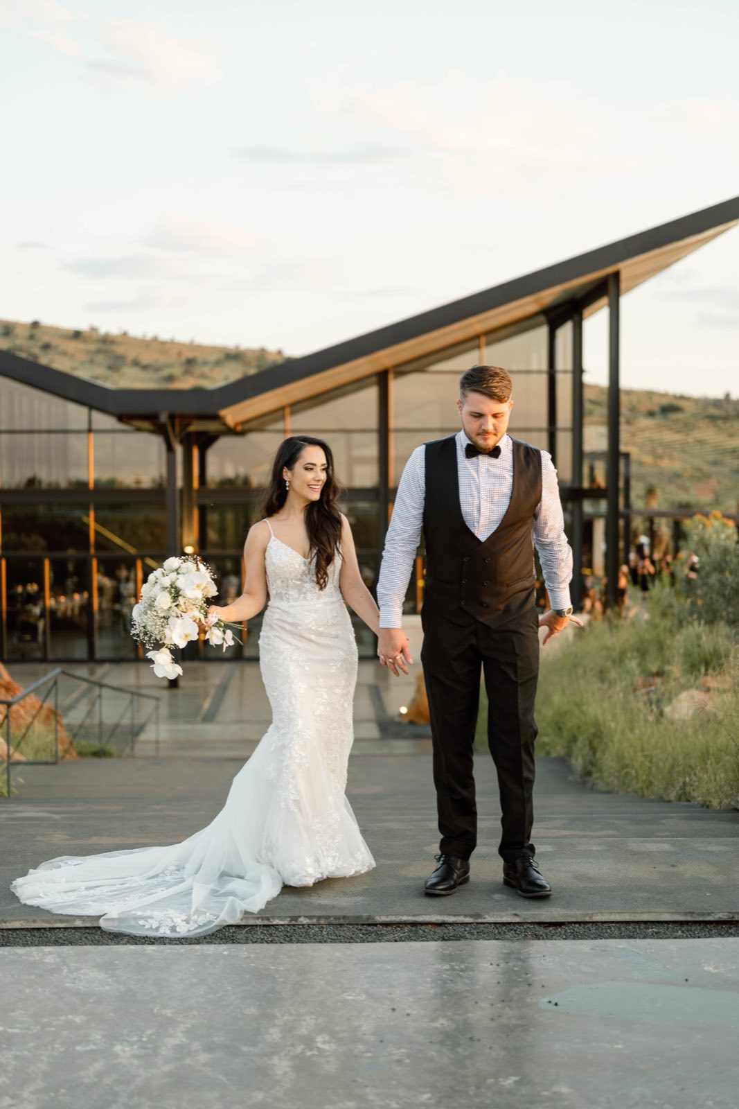 Newlyweds walking outside a modern glass venue