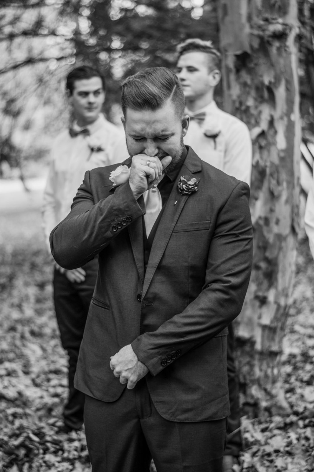 Groom wiping away an emotional moment among the trees