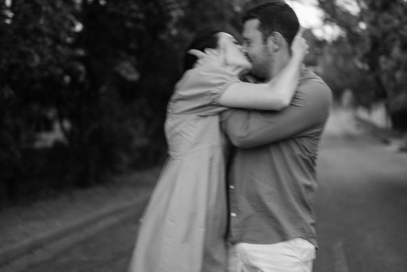 A couple kissing outdoors in a soft black and white photograph